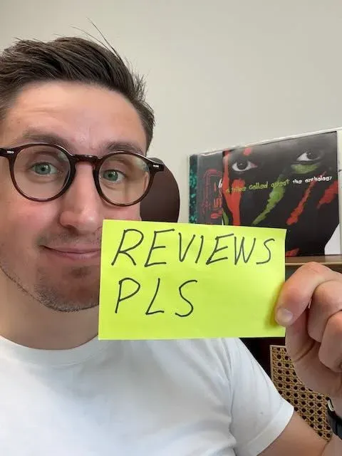 Karri holding up a sticky note that reads “Reviews pls”