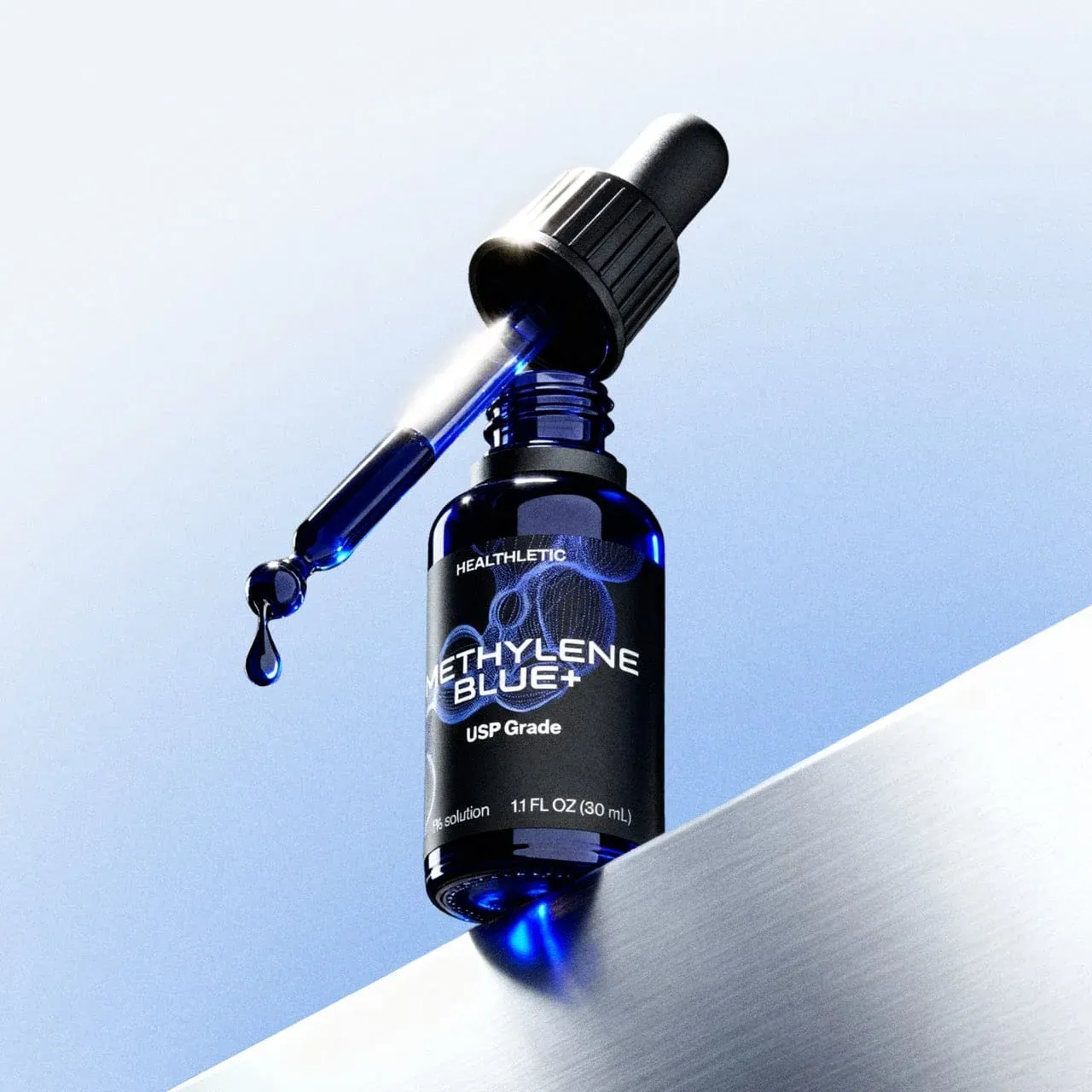 A dropper bottle of Healthletic Methylene Blue+ standing on a brushed metal ledge