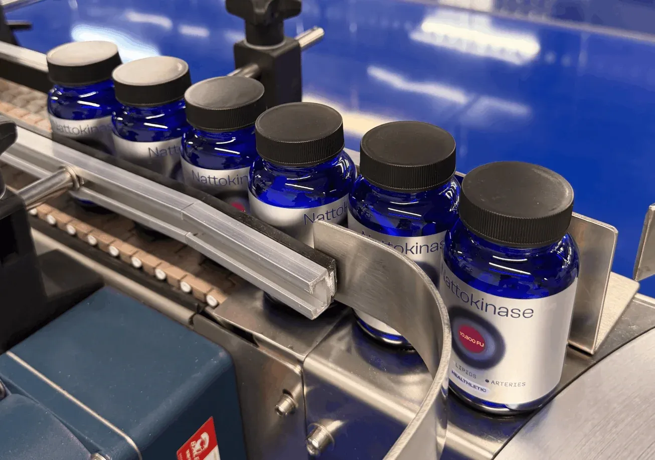 Healthletic Nattokinase bottles moving along a production line conveyor